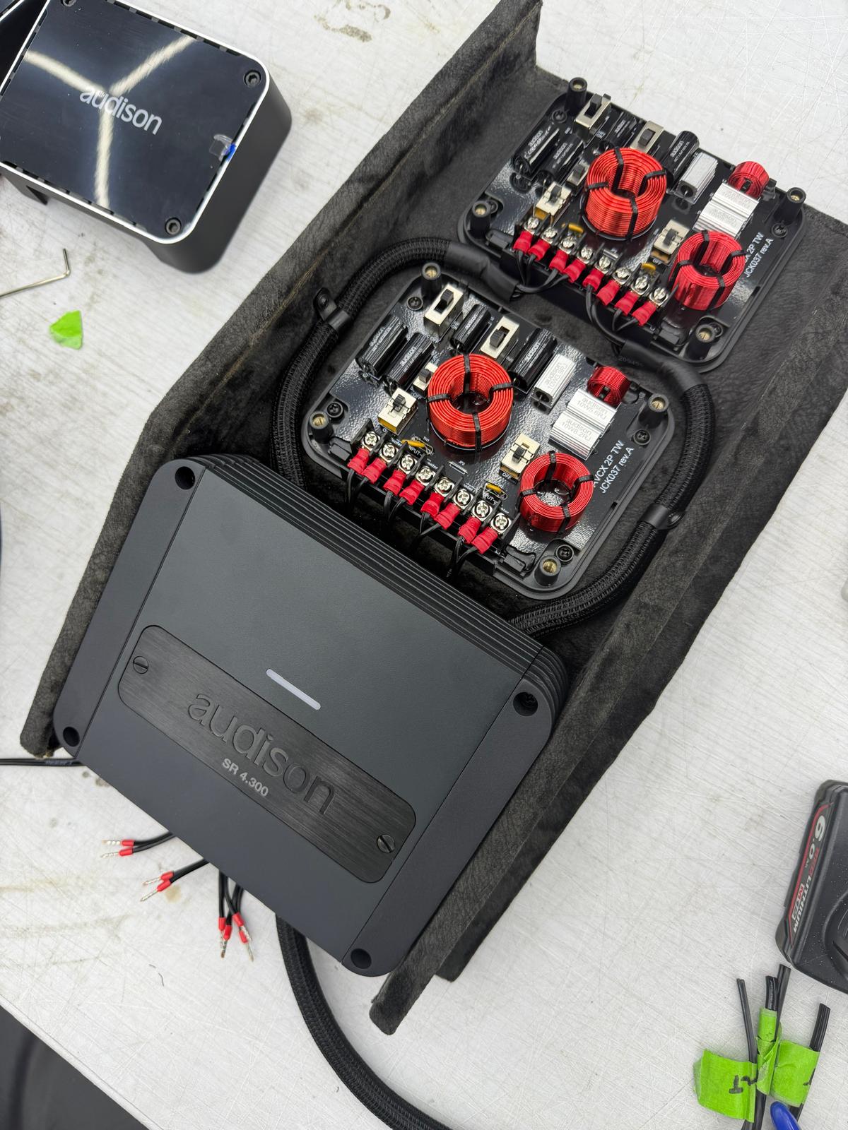 Audison amplifiers and passive crossovers laid out on the bench during a full system build