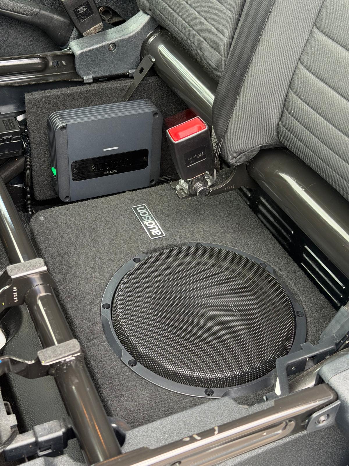 Audison amplifier and slim subwoofer enclosure fitted under a rear seat