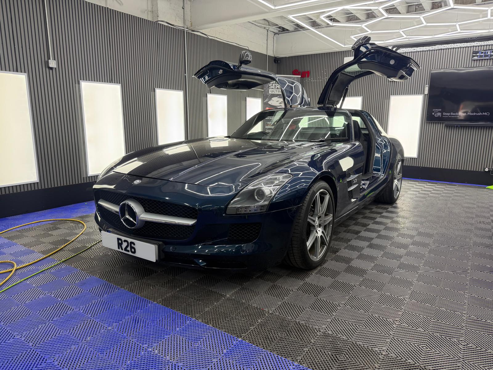 Mercedes SLS AMG with gullwing doors open in the detailing bay